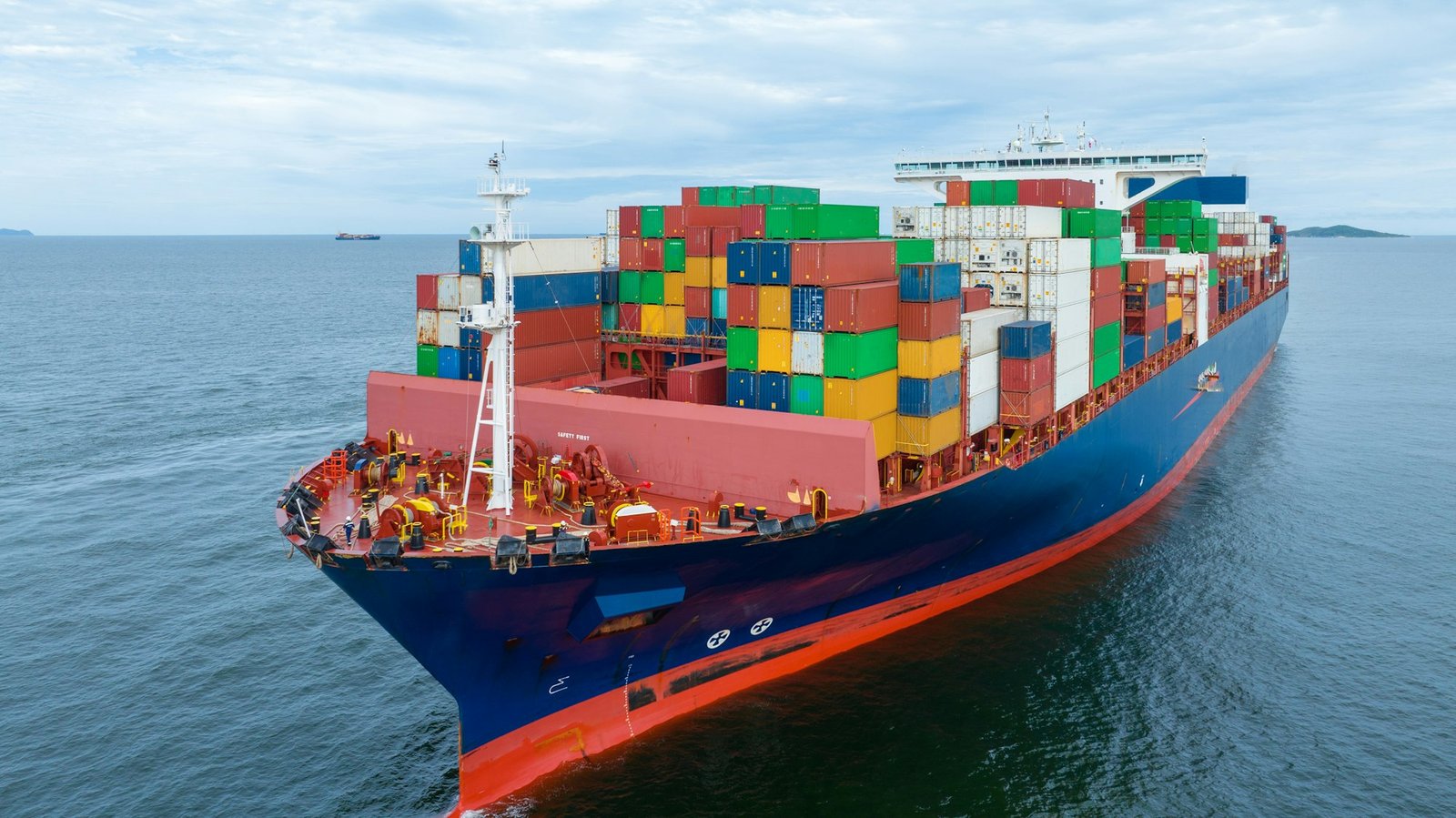 Aerial side view of cargo container ship carrying container from custom container depot