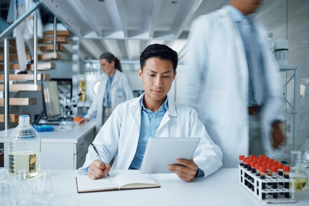 Asian man, tablet and writing in science laboratory for medical virus research, medicine and vaccin