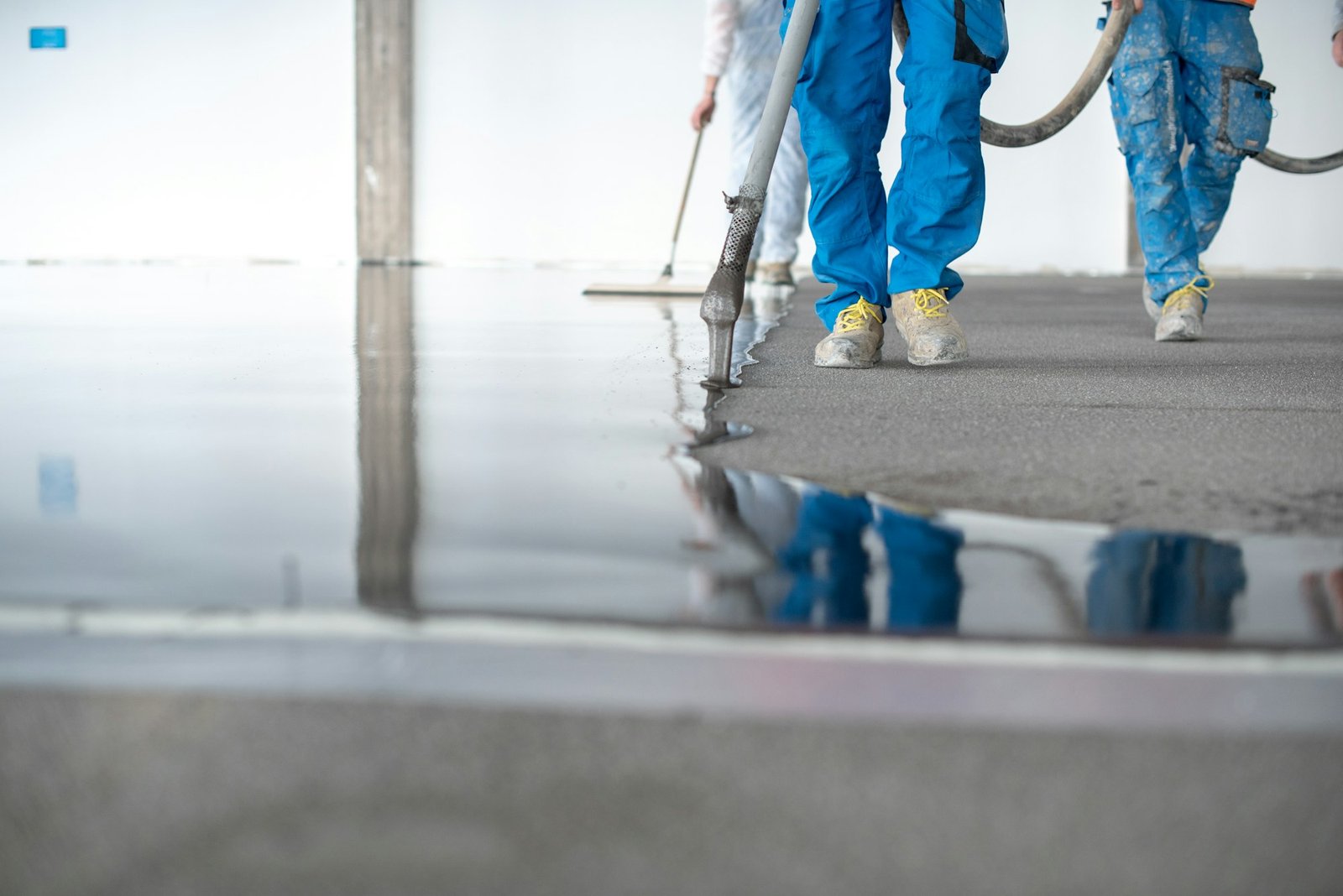 Crop workers pouring self leveling concrete floor