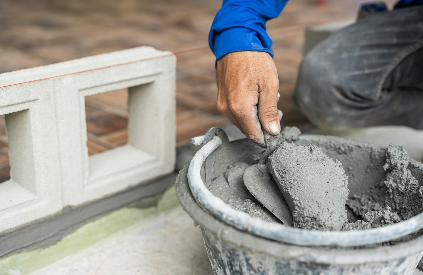 Hand worker with trowel wet cement bucket for masonry brick wall