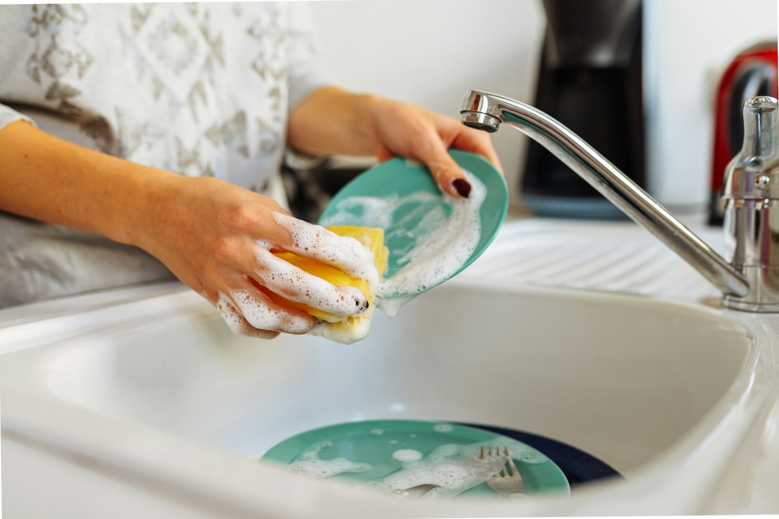 Hands young woman washing dirty dishes in kitchen sink with washcloth and detergent
