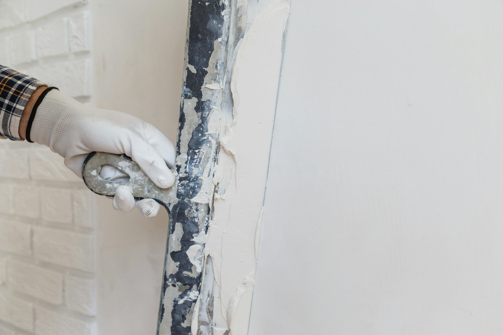 Worker in white gloves performs plastering of the walls of the room