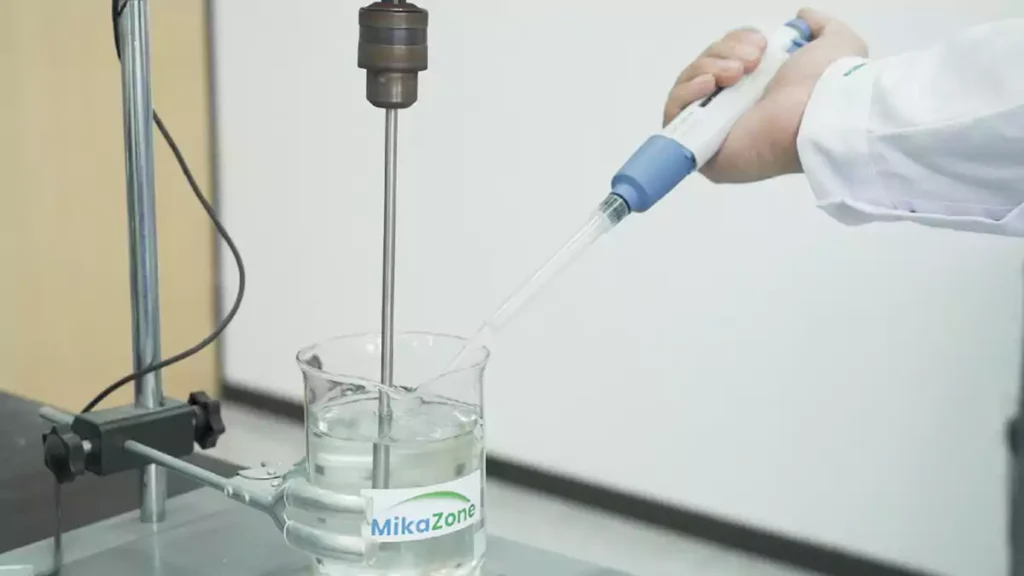 A lab technician in a white coat is using a syringe to inject cellulase into an HEC aqueous solution.