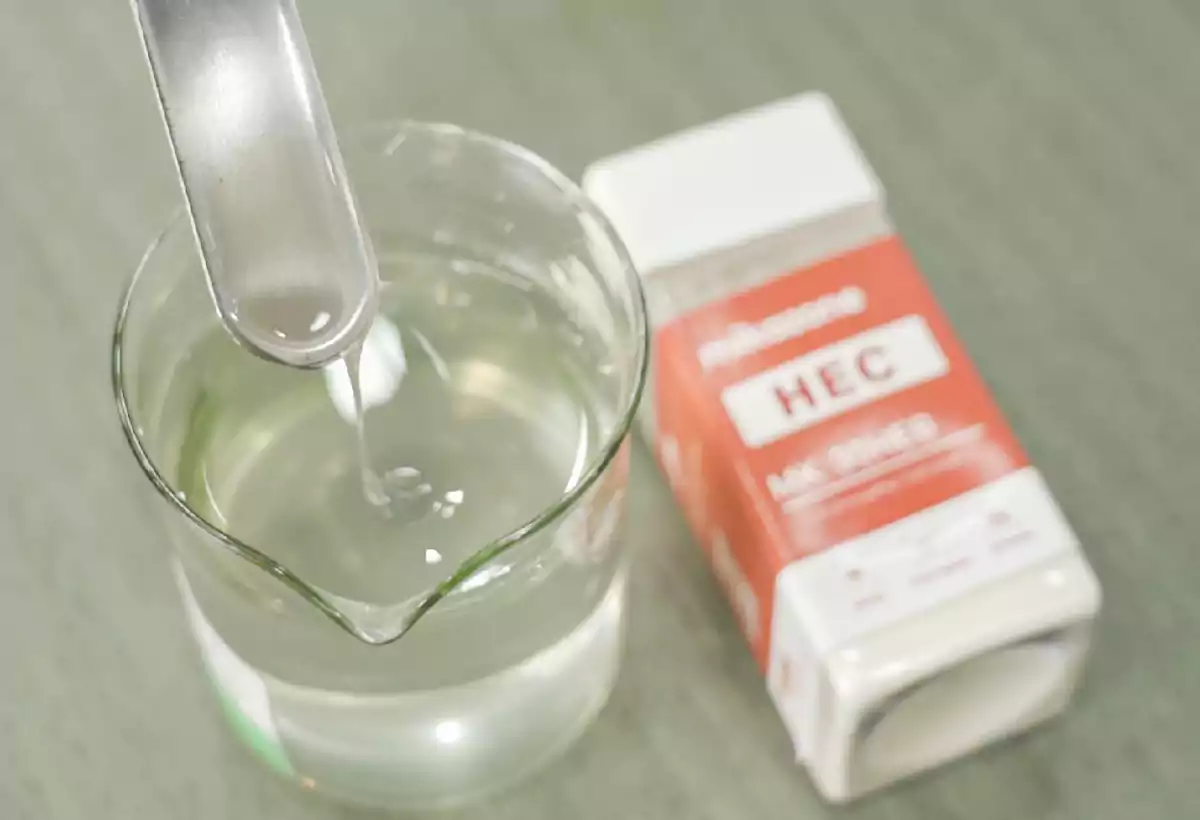 The HEC cosmetic-grade product solution is lifted with a spatula to demonstrate its transparency and viscosity.