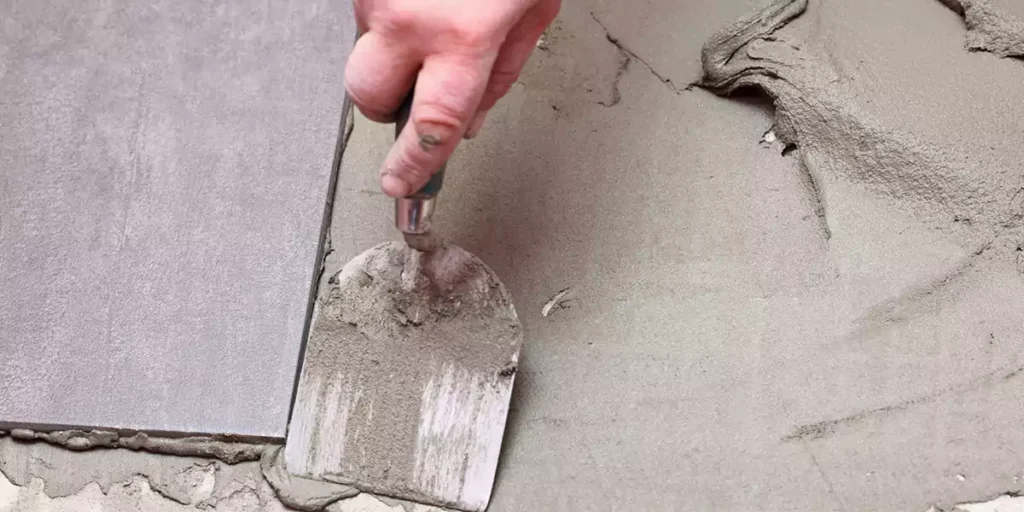 A worker using a small trowel to smooth cement mortar.