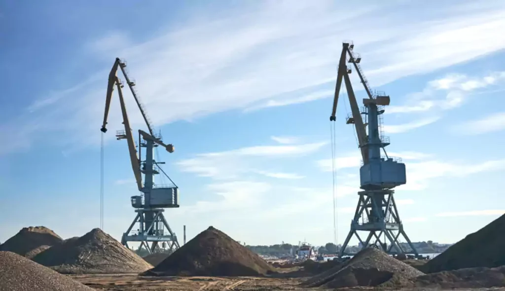 On a construction site with piles of dirt, two drilling machines are operating under the blue sky.